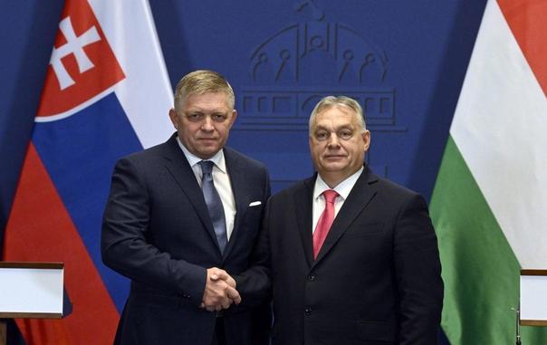 Fico and Orbán shaking hands in front of the flags of their countries.