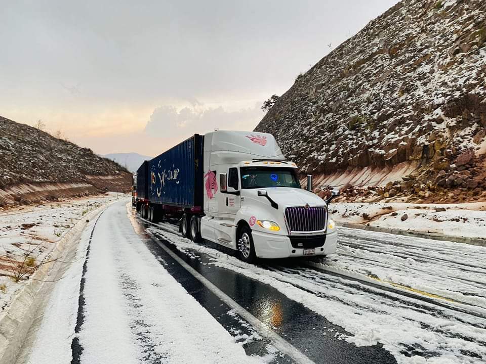 Foto de un camion con un contenedor en el camino