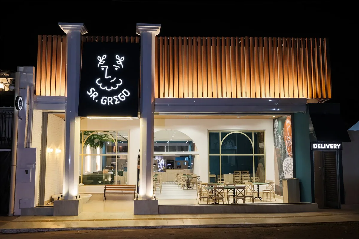 Fachada iluminada de uma loja Sr. Grego à noite