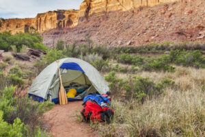 sunrise over river camping in Canyonlands National Park- a tent with canoe paddle and waterproof bags on the shore of Green River