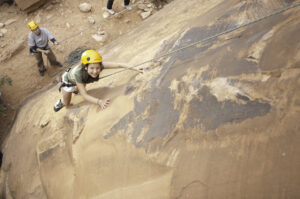 Beginner rock climber ascending sandstone wall in Moab Utah