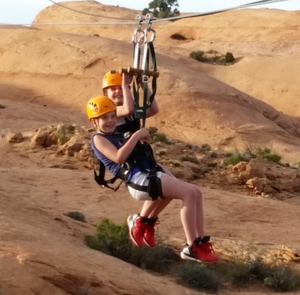 Two kids tandem ziplining in Moab Utah