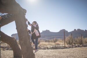 Young girl climbing dinosaur playground at Moab Giants