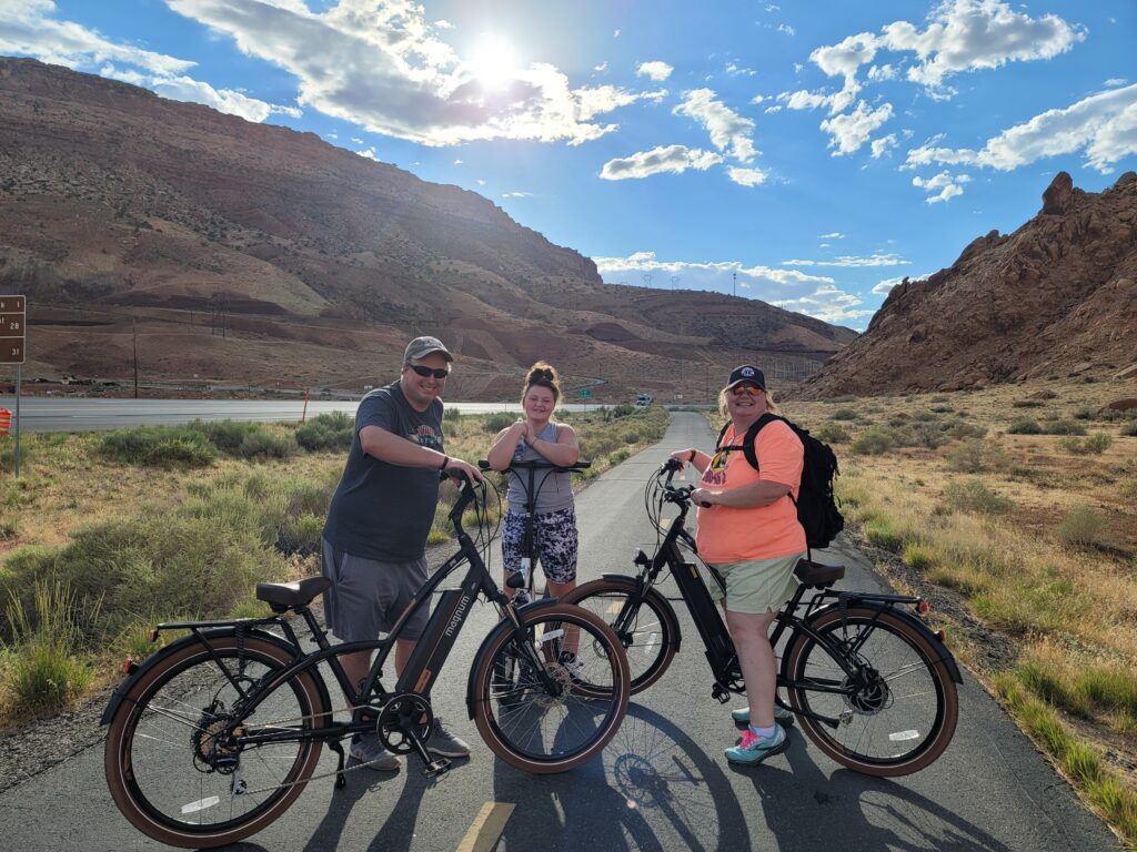 Family of three posing with e-bikes on Moab trail
