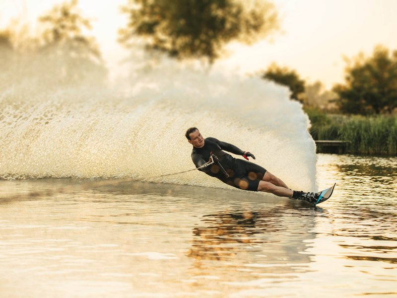 A Person watering skiing, spraying a huge fan of water behind them