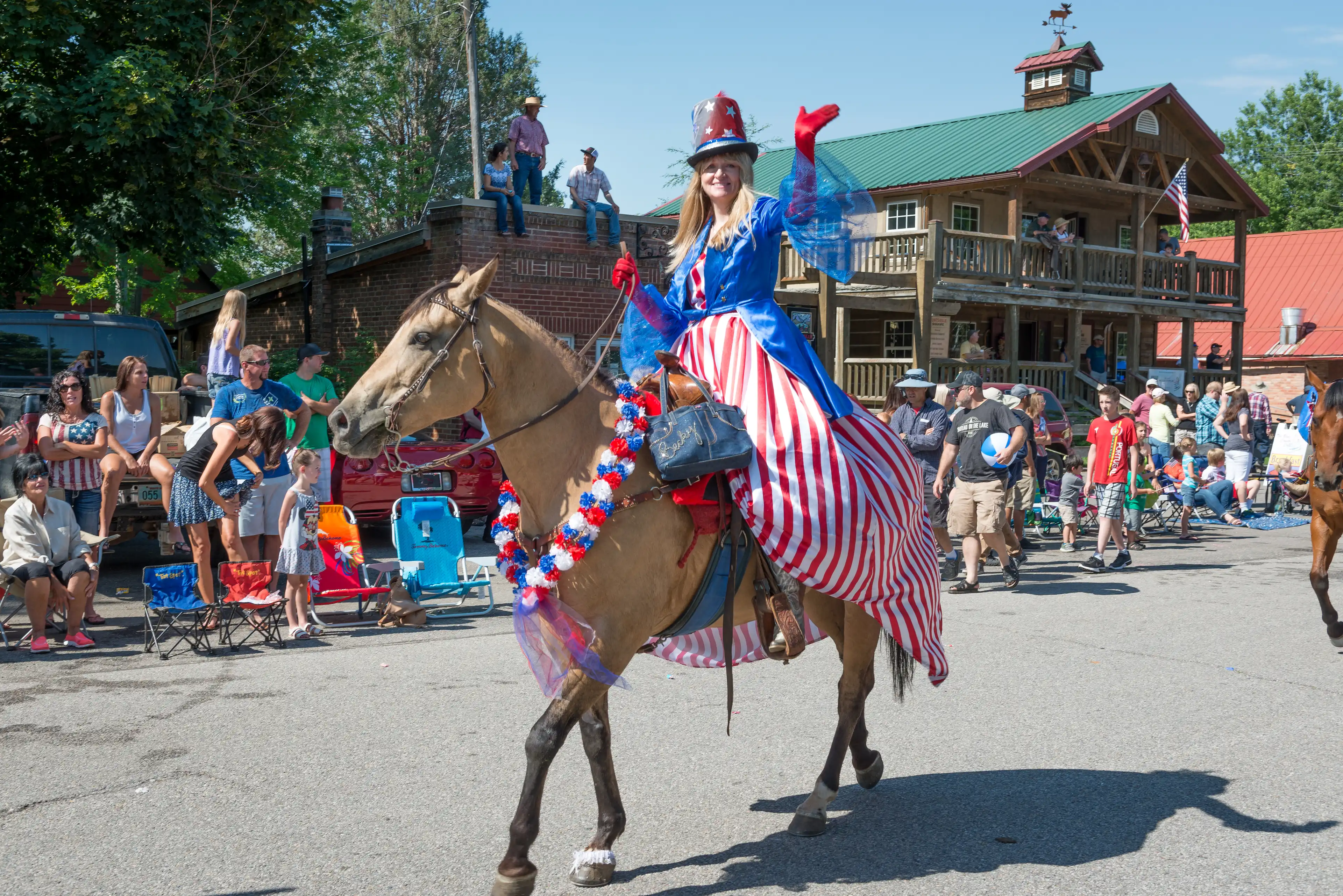 A lady riding a horse down Huntsville town in a American Flag themed dress.