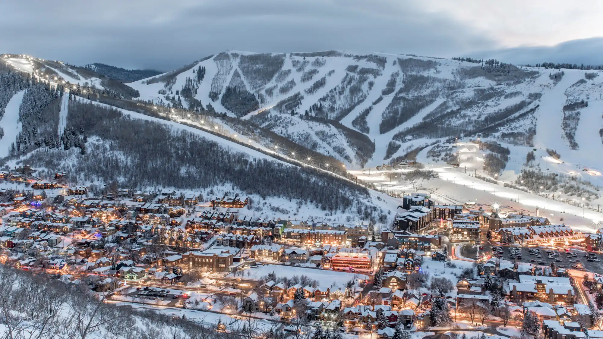Dusk view of Park City, Utah, with snow-covered slopes and twinkling lights of the town below.