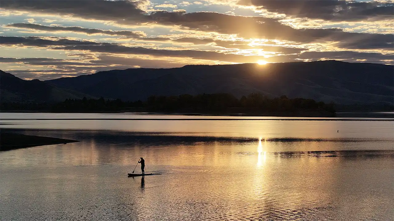 Paddleboarder on Pineview Reservoir in the fall with a beautiful sunrise.