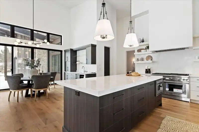 The 6770 E 950 S luxury kitchen with large island and two pendant lights with dining area in the background.