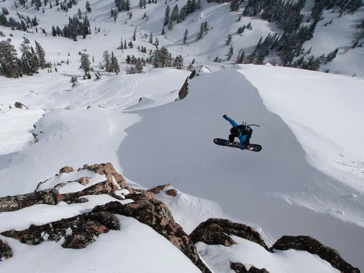 Snowboarder jumping off a cliff at Powder Mountain resort in Eden, Utah.