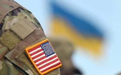 american flag on soldiers arm and flag of the ukraine at backgro