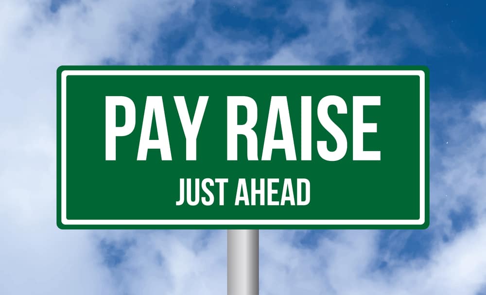 pay raise just ahead road sign on sky background