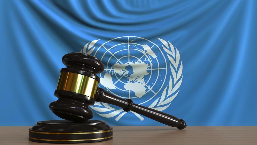 judge's gavel and block against the flag of the united nations. court conceptual editorial 3d rendering