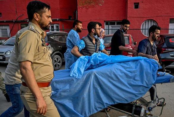 Des ambulanciers et des policiers transportent un touriste blessé dans un hôpital d'Anantnag, au sud de Srinagar, le 22 avril 2025.