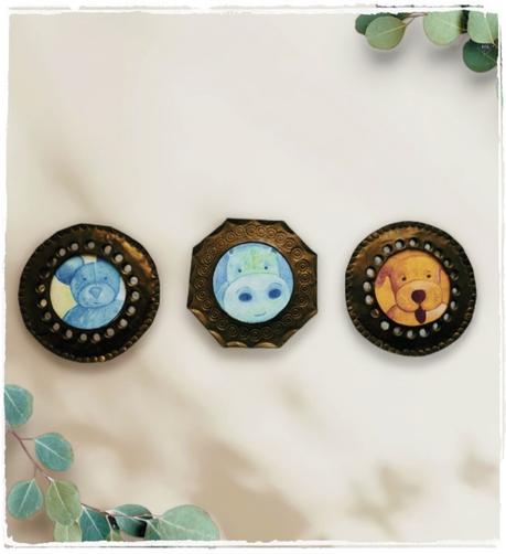 3 cadres en cuivre. Dans le 1er, un ourson bleu, dans le second un hippopotame vert et dans le dernier un chien jaune. Les illustrations  sont aujourd'hui imprimées sur divers supports éco-responsables et personnalisables : https://itkacreations.tpopsite.com