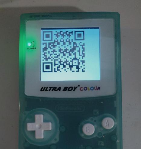 Photograph of a Game Boy showing a QR Code on it's screen