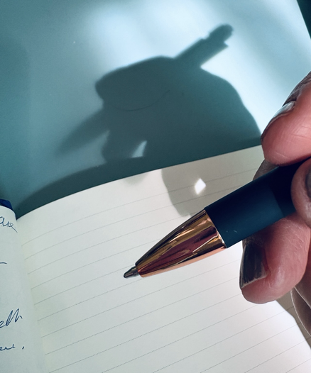 Hand mit Kugelschreiber will schreiben, Schattenbild dahinter