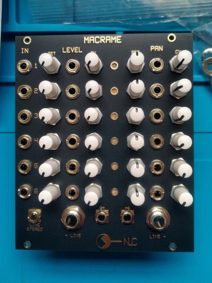 A eurorack mixer module called MACRAME by NLC.
The faceplate is black with gold lettering.
There are 24 white knobbed potentiometers in four columns of six, 18 jack sockets and a column of 6 LEDs.
At the bottom are three more 3.5mm sockets and two 6.35mm sockets.
The rightmost columns of jacks is headed IN, the next column LEVEL, and the final column PAN.