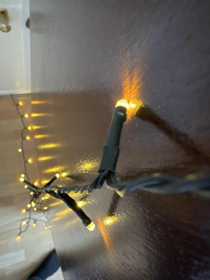 Glowing fairy lights hanging from a wooden shelf.