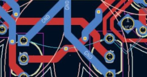 Close-up of a densely routed PCB layout in a CAD tool. Red top-layer and blue bottom-layer traces crisscross with multiple labeled GND vias and overlapping signals. Silkscreen outlines and drill holes suggest a complex, double-sided board in active development.