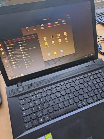 Starý Lenovo 17" notebook s Linux Mint, na obrazovke je štart menu a okno nastavení.