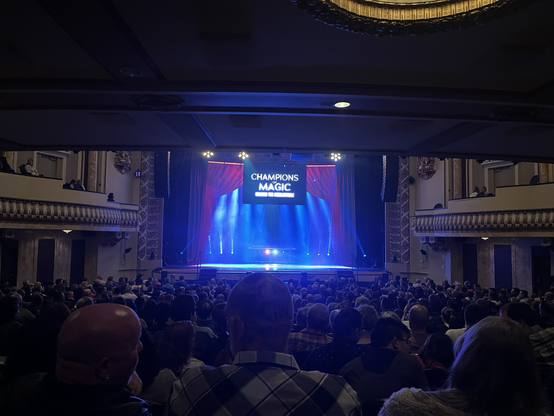 A photo of the royal theatre stage with the sign for champions of magic