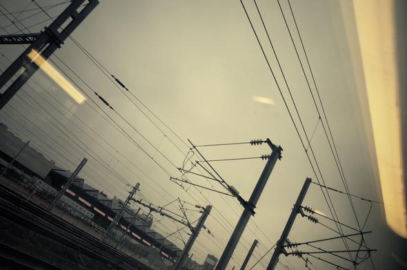 Lumières reflétés, câbles d'électricité, poteaux, rails... Depuis la fenêtre, un soir au train.