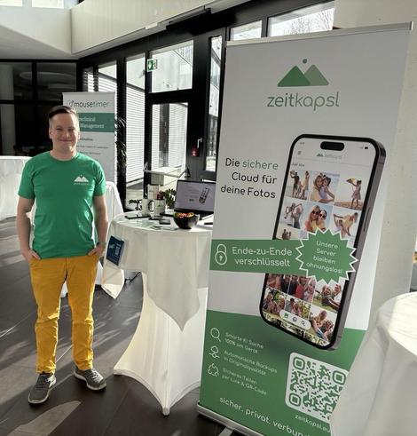Co-Founder peter standing next to the zeitkapsl roll up banner.