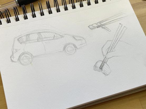 Sketchbook with pencil sketch of a car, chopsticks holding fried squid and grouper fish filet