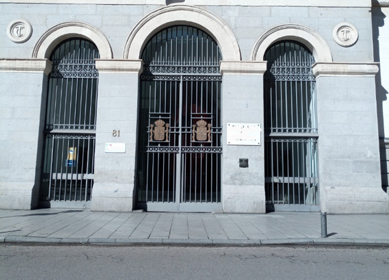 A central metal double gated dooway with a smaller similar single gate one to each side of it making 3 entrances of fairly simple metal railings, and the number 81