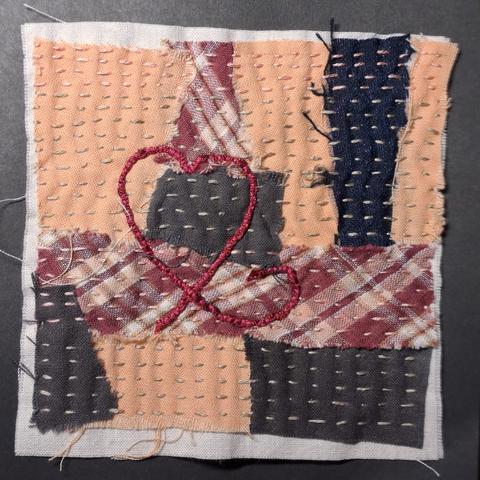 Ein paar Stoffschnipsel, die für eine Stoffcollage auf ein Stück Untergrundstoff aufgenäht wurden.
