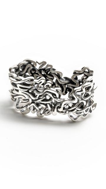 A solid sterling silver heirloom napkin ring, designed as a sculptural tribute to the Mississippi River, rests on a white background. The design interweaves seven historic pathways of the world's 10th largest river into an intricate and functional sculpture.
