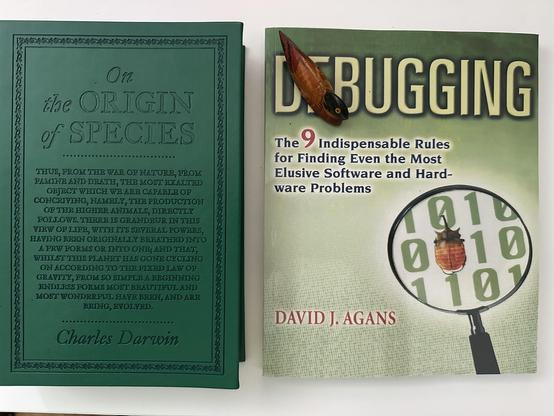 Two books - „On the origin of species” by Charles Darwin on the left and „Debugging” by David J. Agans on the right.