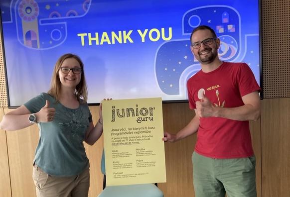 Daria a Honza drží ceduli junior.guru a za nimi je televize s EuroPython grafikou a nápis THANK YOU