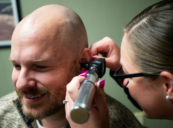 a person having their ear checked by a doctor