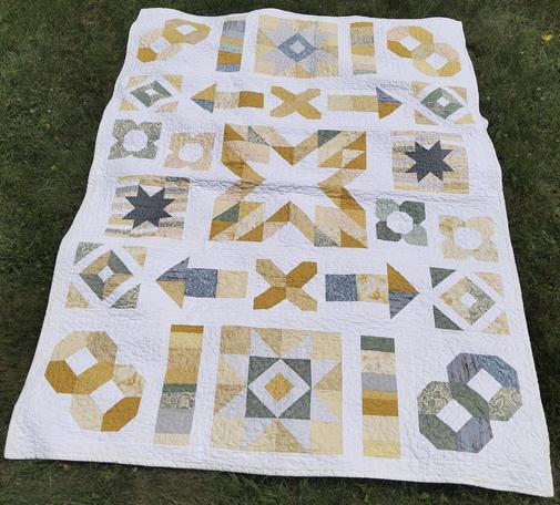 a quilt, it is light gold and grey shapes against a light background