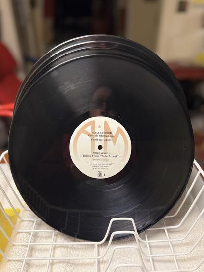 Several freshly cleaned vinyl LPs drying in a dish rack. The foremost is Chuck Mangione's "Feels so Good" on A & M records