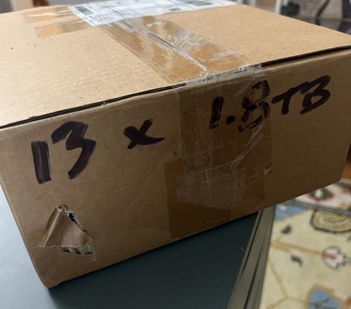 Photo of a cardboard shopping box. It’s still taped and sealed. In black magic marker the letters 1 3 X 1 point 8 T B are written on one side