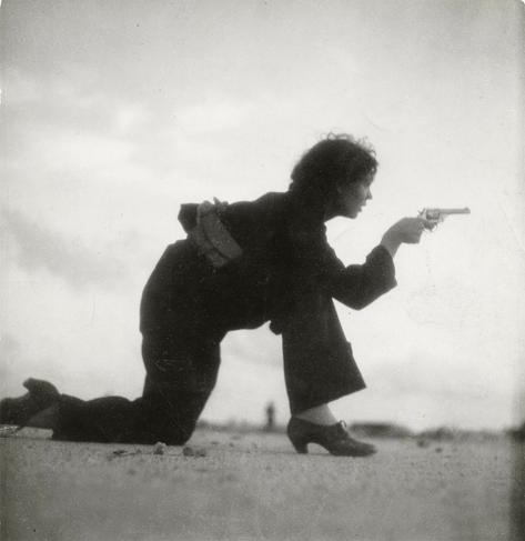 Woman training for a Republican militia by Gerda Taro (1936). The woman is on bended knee, aiming a revolver. By Gerda Taro - https://kuenste-im-exil.de/KIE/Content/EN/Images/objects/taro-gerda-militiawoman-foto-en.jpg, Public Domain, https://commons.wikimedia.org/w/index.php?curid=3322763