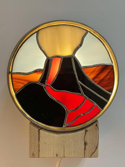 Houten voet, onder cirkelvormige lamp. Met in de lamp een stuk Tiffany glas in de vorm van een vulkaan.