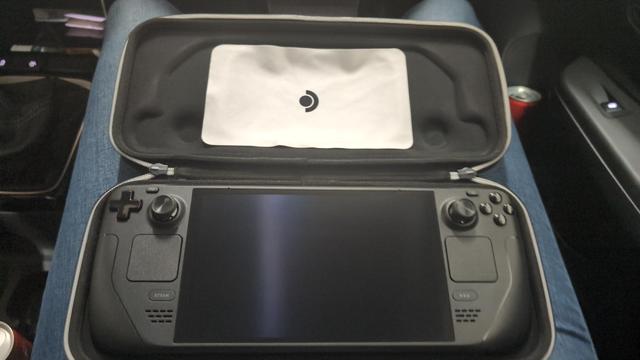 A Steam Deck in a case on someone's lap in a car.