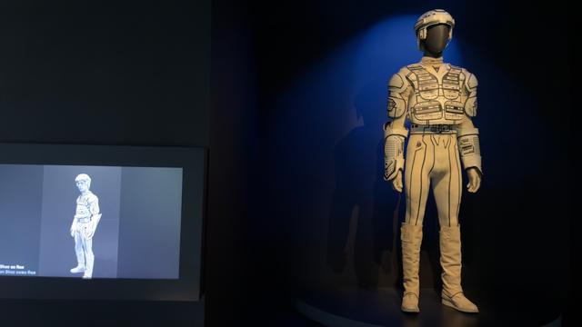 Suit from Tron, with a placard that says it was made with shoddy off the shelf things, with cinematography and after effects making it look real and glowing.