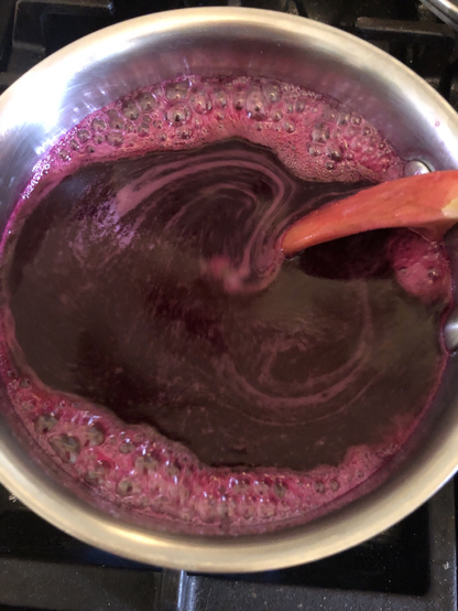 Deep purple prickly pear syrup simmers on stove