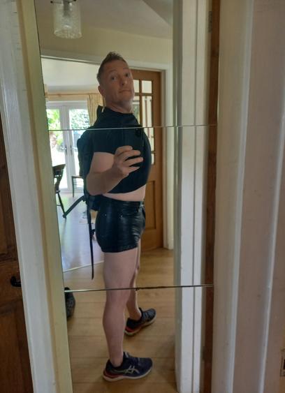 Me posing in the mirror in leather short shorts and black cropped tee. Rucksack on my back, trainers on my feet
