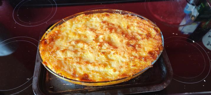 A photo of an oval dish with a baked vegetarian cottage pie in it. The top is covered with cheese.
