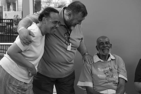 a photograph of three people, particularly Mel King, seated, smiling with eyes squinting. Haakon Karlsen is next to him, with a hand on his shoulder, smiling with a big smile at Mel, and Pamela King, coming into the photo with Haakon's arm hugging her shoulder, and she is smiling at the crowd. Boston, US, 4 August 2015, at FAB11, the international fab lab conference and meeting. not visible: the event was to commemorate King's contribution to Black digital literacies and many people are here also taking photos of the occasion. photo Cindy Kohtala