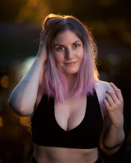 A finnish woman posing in front of a blurry pond on a summer evening smiling
