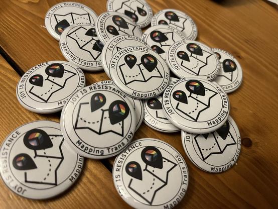 Pile of buttons. MTJ logo with words, “Joy is Resistance” “Mapping Trans Joy”