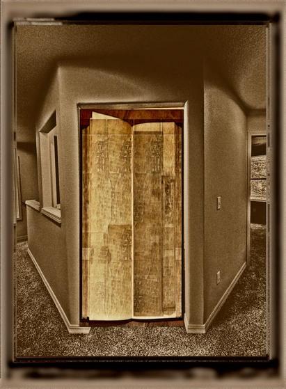 Aged photo of a doorway to a room. The doorway space is filled with an open aged book with indecipherable text.