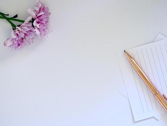Whitespace between a flower and pen and paper.